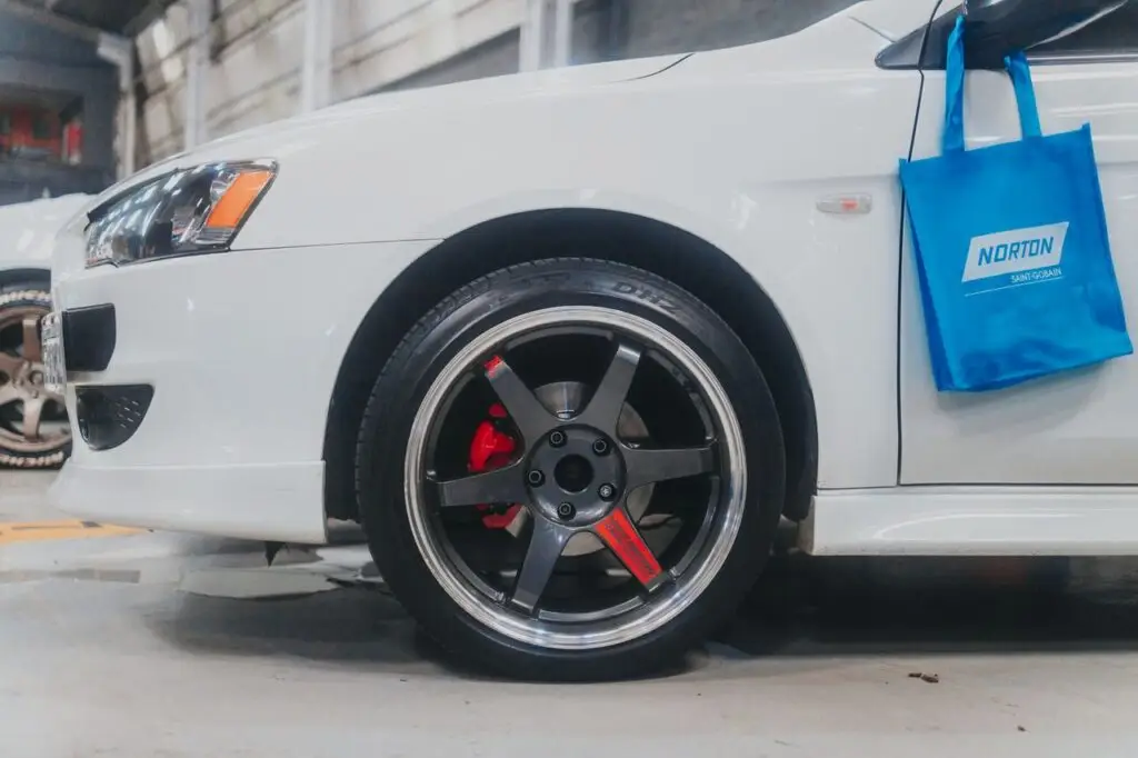 Detailed close-up of a white car's alloy wheel with visible brake calipers in a garage setting.