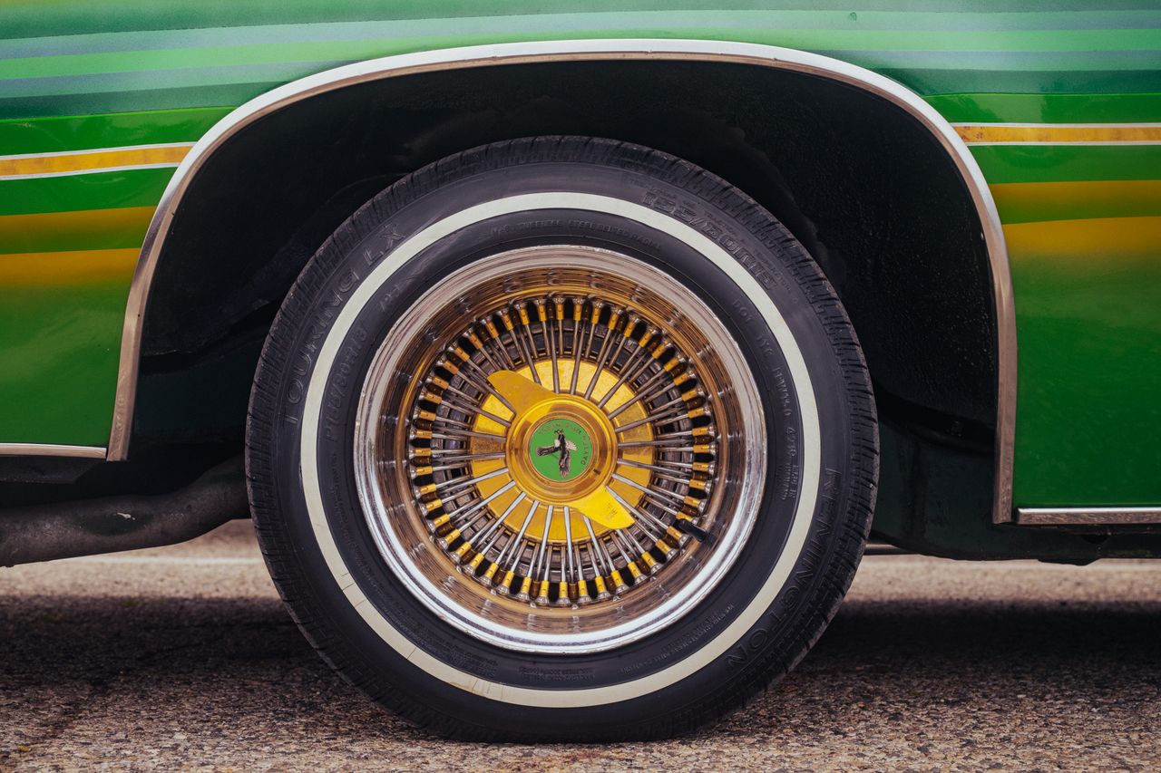 Detailed shot of a vintage car wheel with vibrant green and yellow colors.